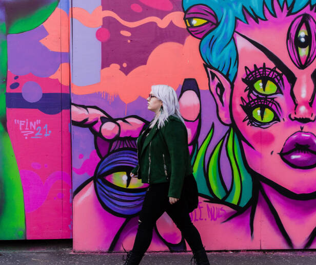 Person wearing black walking in front of vibrant street art