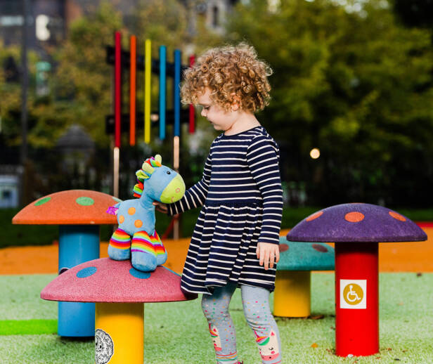 A young child playing in a playground with a cuddly toy