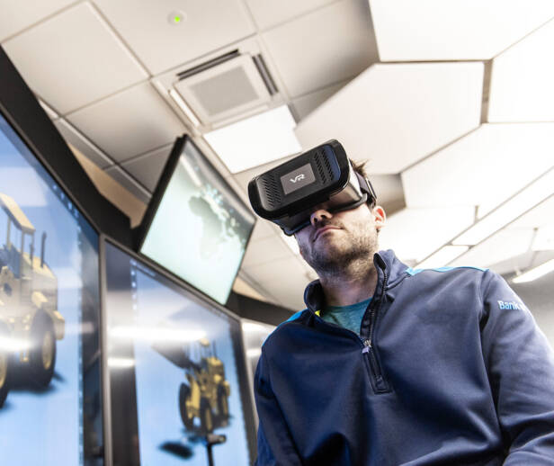 Person wearing virtual reality goggles looking at a 3d render of a construction vehicle