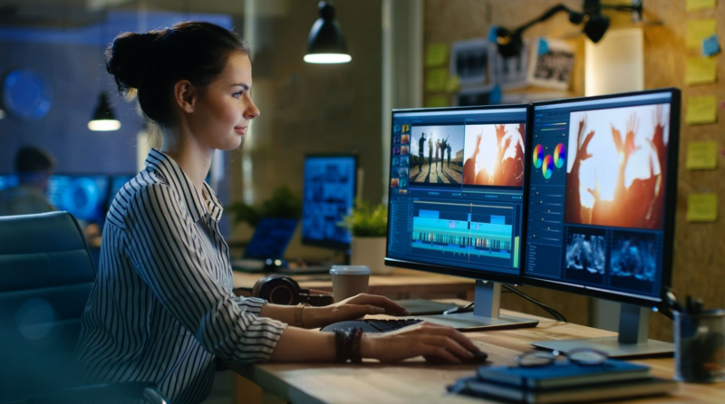 A person working at a desk with dual computer screens