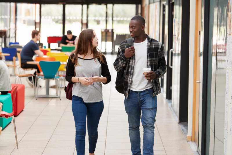 Two students are in conversation as they walk.